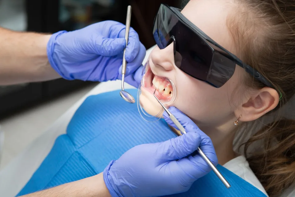 A child receiving dental care wearing protective goggles during treatment.